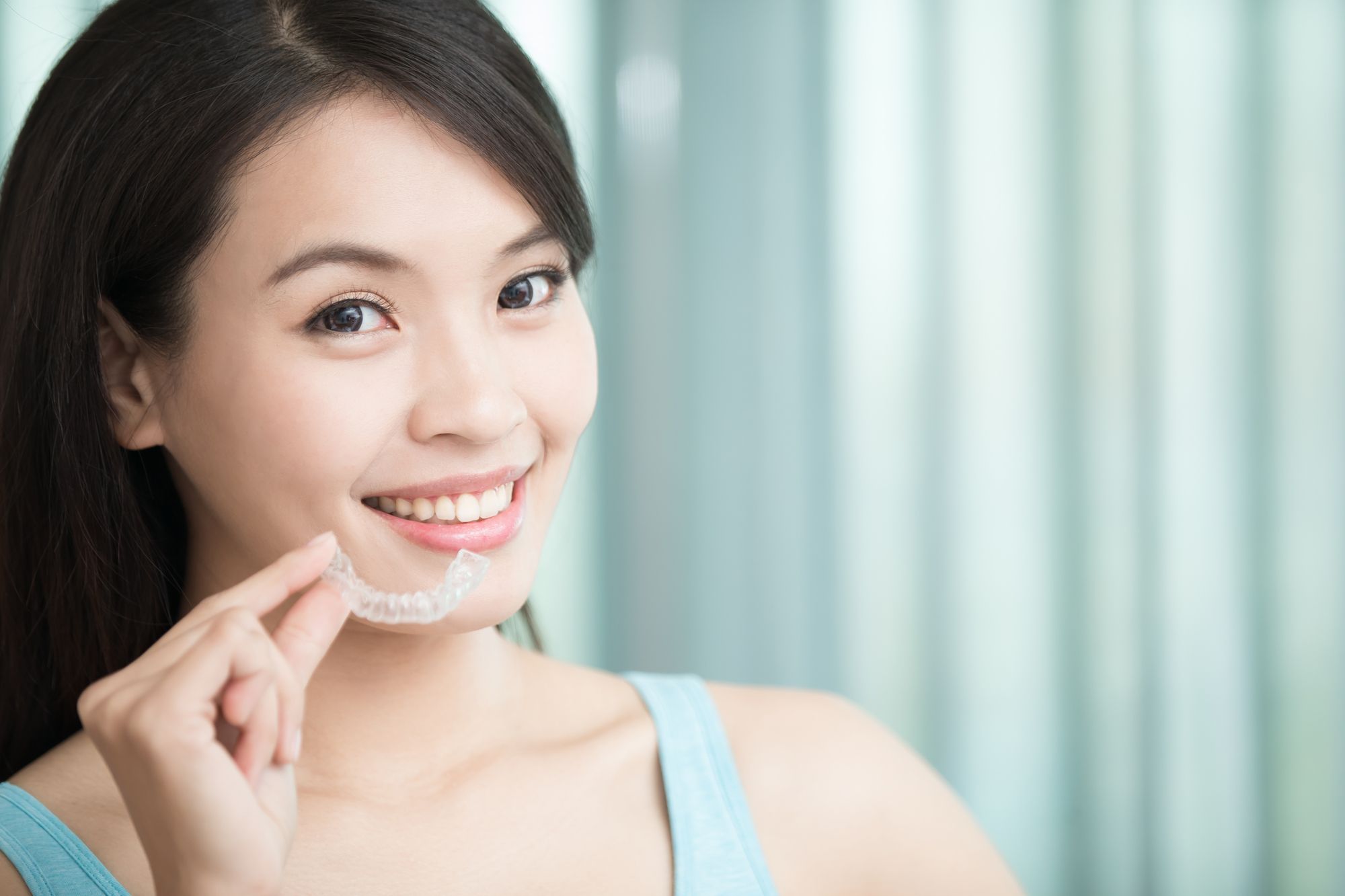 woman smiling with putting her Invisalign clear aligners in